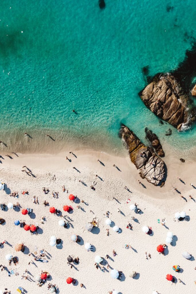 budget travel in Africa: Aerial shot of a beach with colorful umbrellas and people enjoying the summer sunshine.