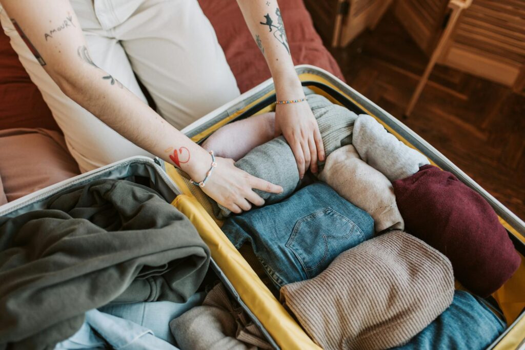 Packing Light for Travel: Close-up of a person packing various clothing items into a suitcase, ready for travel.