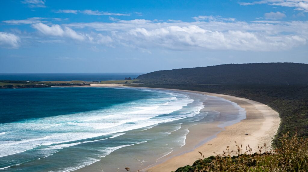 Scenic Road Trips in New Zealand: a view of a sandy beach with waves coming in from the ocean