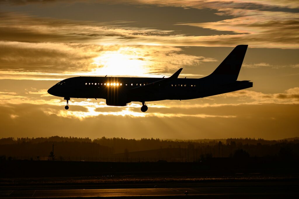 Cheap Flight Deals: airplane flying over the city during sunset