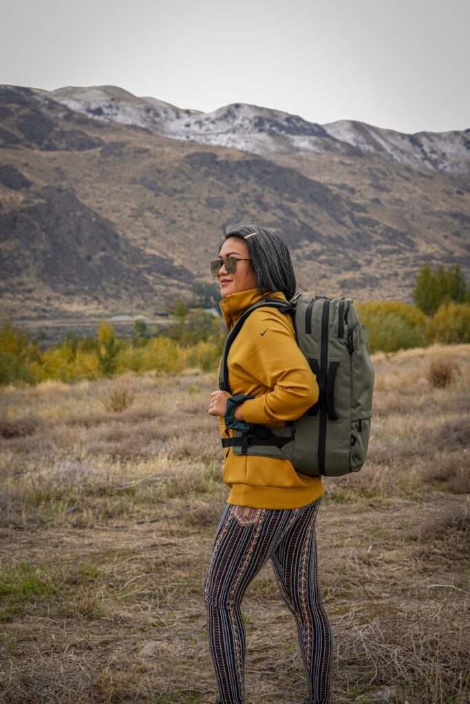 Solo Travel Safety Tips: woman in black and white plaid skirt with black backpack standing on green grass field during