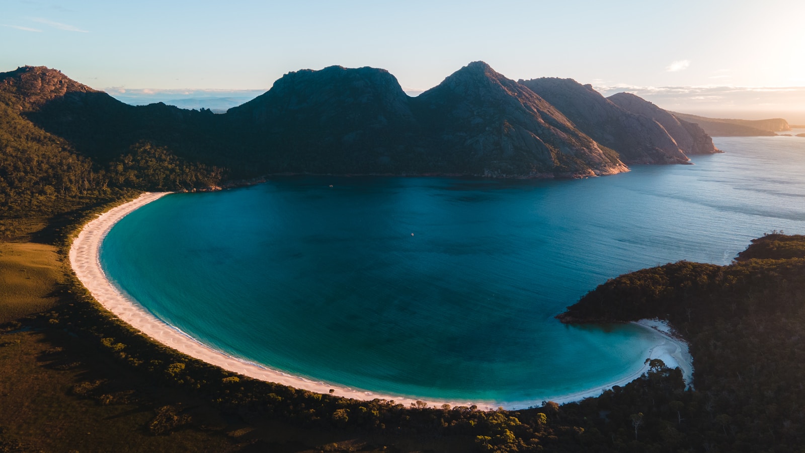 Tasmania Travel Guide: blue body of water near mountain during daytime